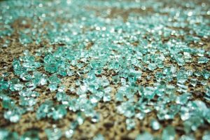 Shattered glass from a car window lays scattered on the sidewalk.