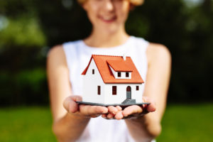 Photo of a young woman holding a miniature house